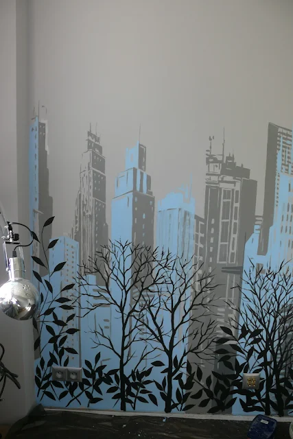 Malowanie obrazu na ścianie w sypialni przedstawiającego panoramę miasta, 