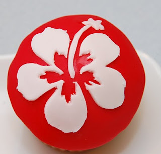 red fondant cupcake with white hibiscus fondant cutout transferred onto it