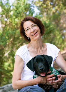woman hugging black Lab puppy