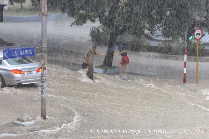 Un oficial de las Fuerzas Armadas Revolucionarias ayuda a una joven en la Calle J en el municipio Plaza de la Revolución, durante las lluvias caídas, en La Habana, Cuba, el 29 de abril de 2015. Un oficial de las Fuerzas Armadas Revolucionarias ayuda a una joven en la Calle J en el municipio Plaza de la Revolución, durante las lluvias caídas, en La Habana, Cuba, el 29 de abril de 2015.