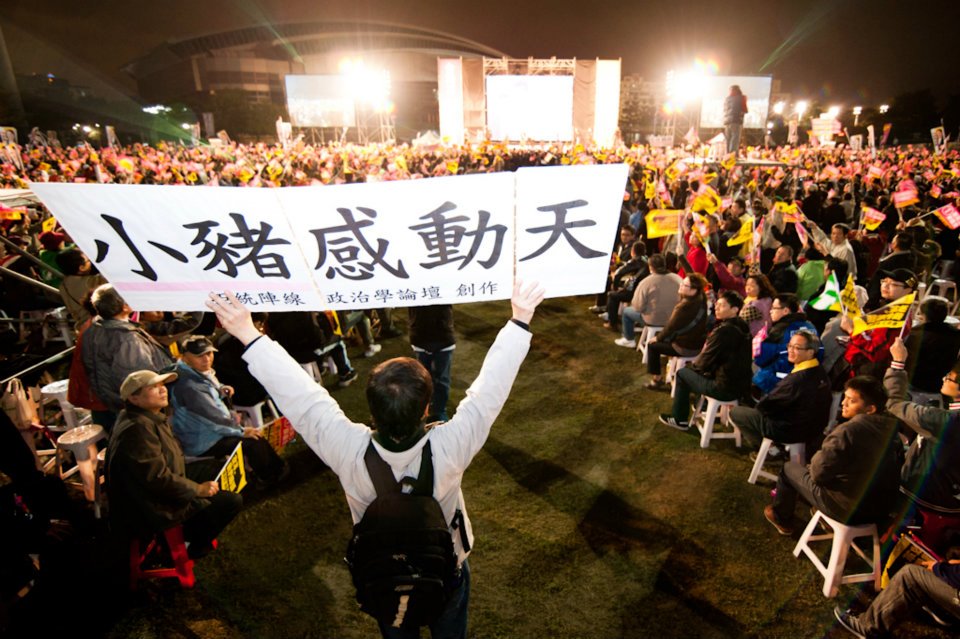 下陳立民 Chen Lih Ming (陳哲) 於2012年總統大選在造勢場高舉「小豬感動天」此為回應「三隻小豬」文宣。選舉後蔡英文主編記錄 2012 選戰相片集《一直同在》中本照片獲選為選戰終結照