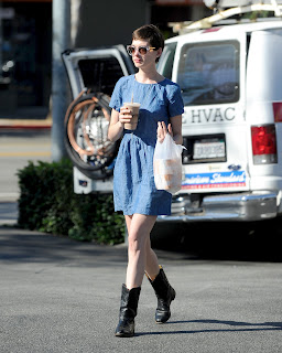 Anne Hathaway in a blue dress black boots and with sunglasses