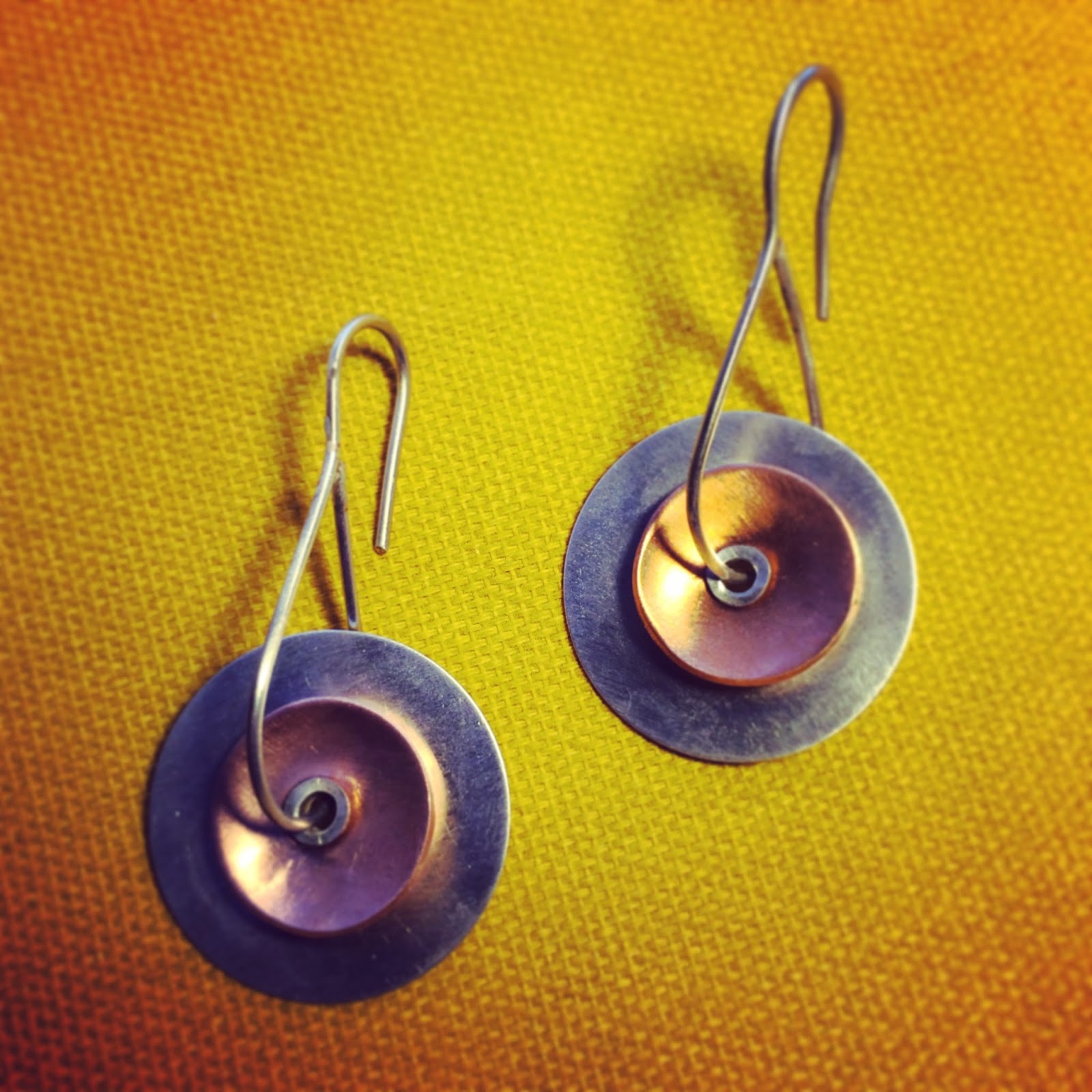 Tube riveted copper and silver earrings Two disc earrings made from copper and silver using a tube rivet to connect and thread the earwires through.