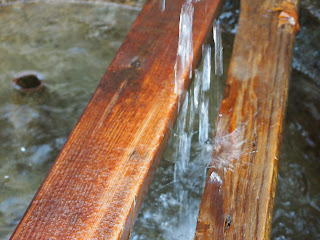 Water falling into the large bowl splashes on boards used to hold water jugs being filled. 