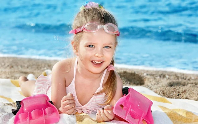 Meisje met zwemspullen op het strand