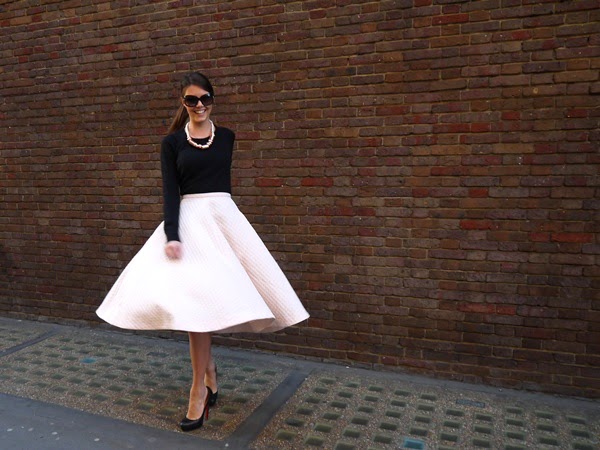 Pale pink midi skirt and black cashmere sweater in Mayfair