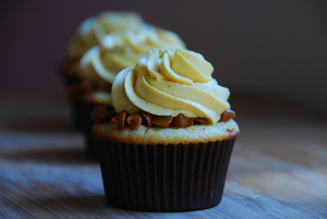 close up of cupcake in brown wrapper with swirl of white icing on top