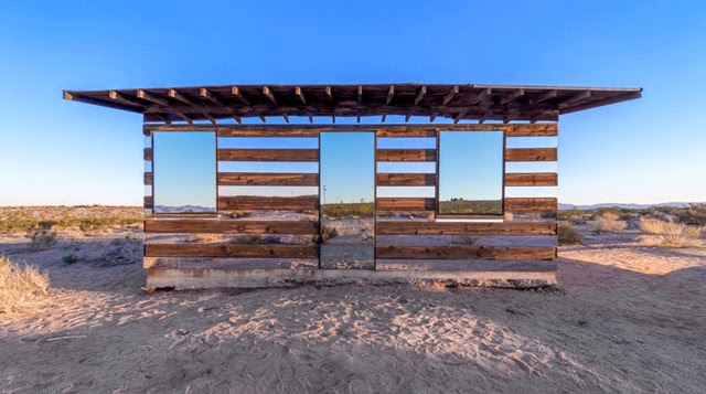 Cabaña transparente de madera y espejos en un paisaje desértico