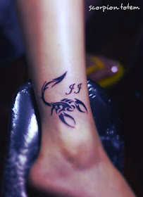 A scorpion totem tattoo on the ankle with letters.
