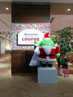 丸の内の docomo LOUNGEにあるサンタさんの服を着用した Android のロボットの画像。