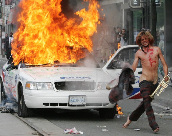 coche de policia ardiendo y tipo extraño con trompeta