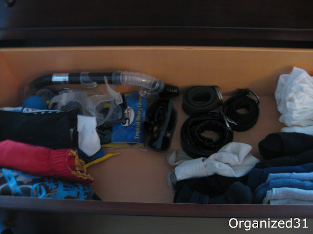 an organized dresser drawer full of clothes and a scuba mask and snorkel