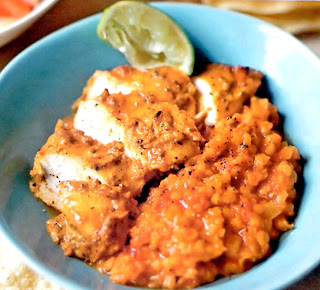 Classic chicken curry served with cooked dhal (lentils) in a bowl garnished with a lime wedge