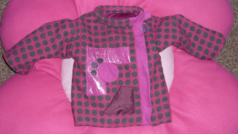 manteau rose à pois gris, avec motifs graphiques sur le devant