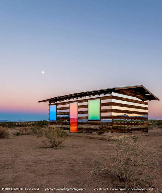 Cabaña transparente de madera y espejos en un paisaje desértico