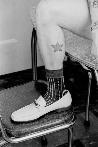 Black and white photo of a man's calf with simple star tattoo Black and white photo of a man's calf with simple star tattoo