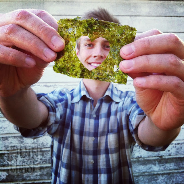 A man holding a sheet of seaweed with a heart cut out of it.