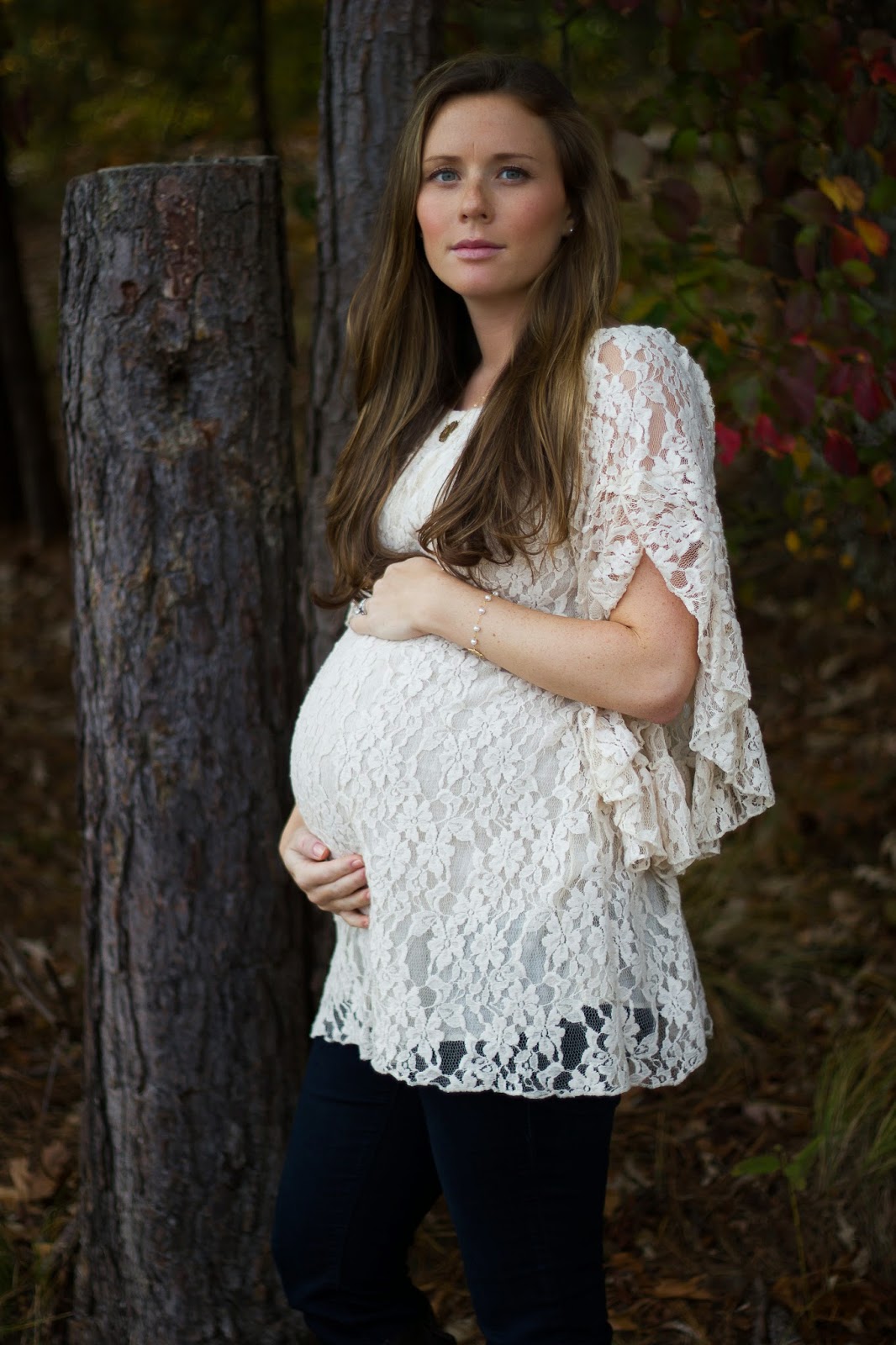 Moody maternity photo woman in lace dress in woods 