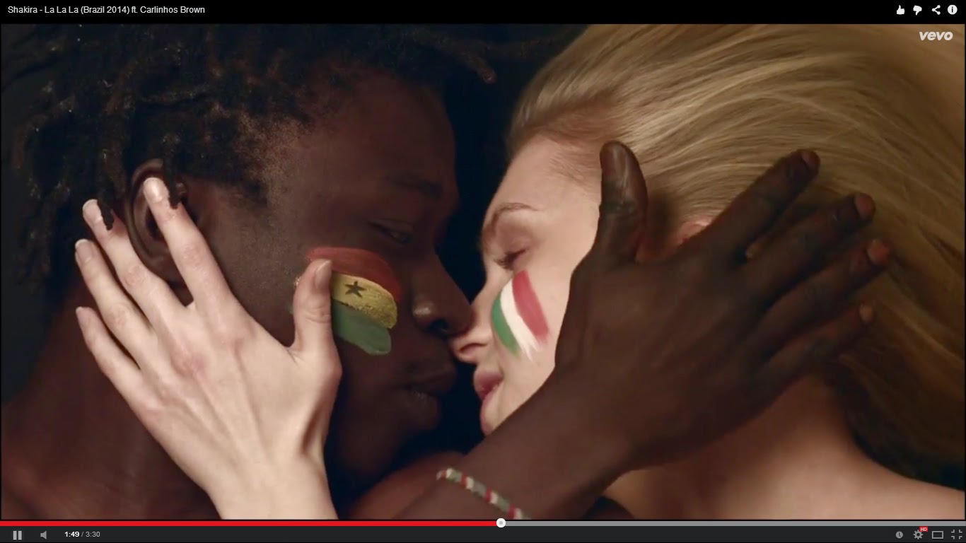 Um beijo entre um homem negro e uma mulher branca, com as bandeiras de seus países pintada no rosto. - Blog Mineira sem Freio