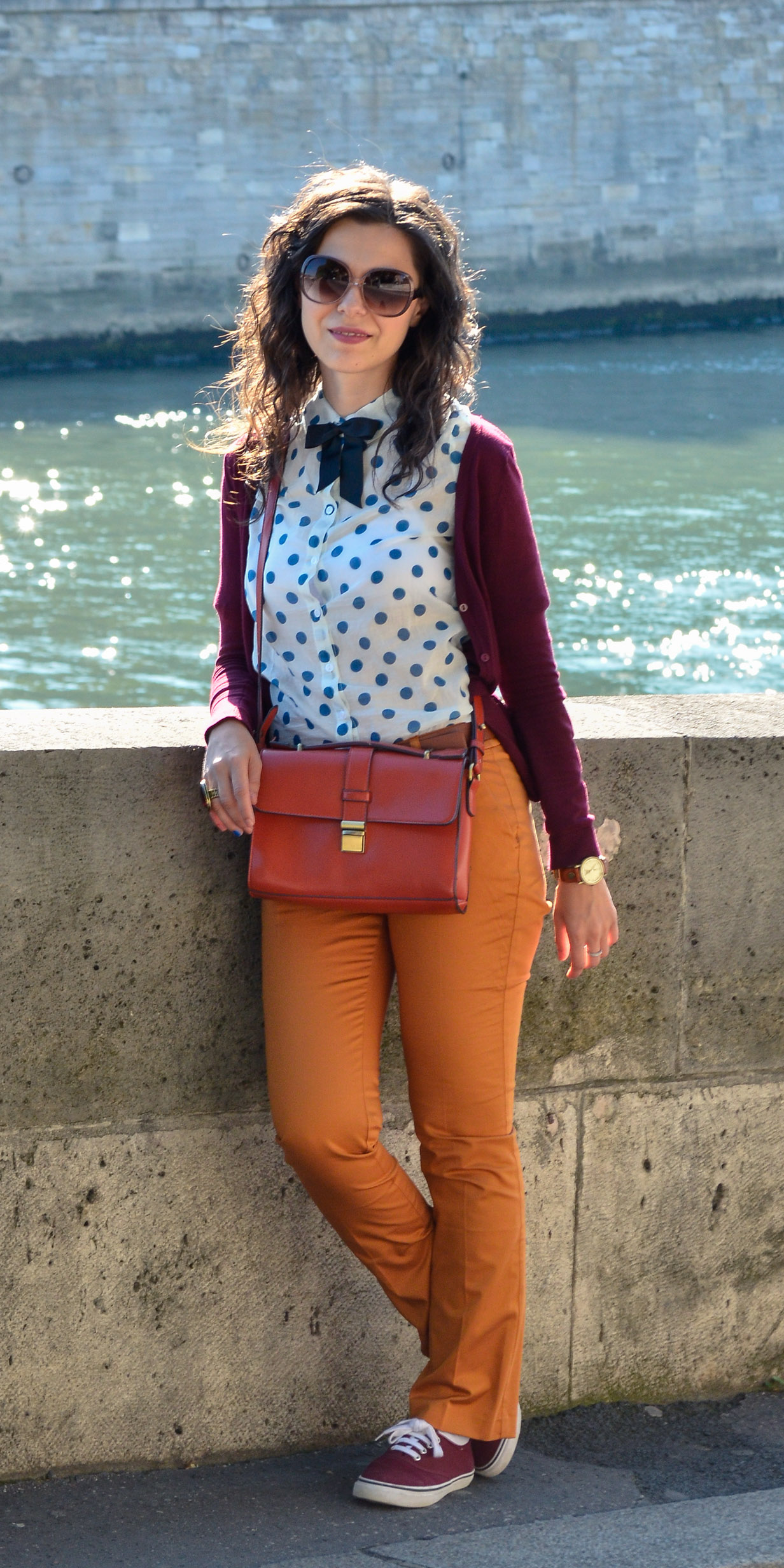 preppy fall outfit in Paris mustard pants burgundy sweater sneakers H&M orange satchel bag dotted shirt blue dots black bow tie champs elysees jardin de tuileries eiffel tower