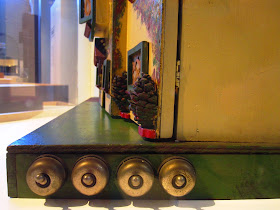 Side view of a vintage doll's house, showing a row of four light switches mounted on the base.