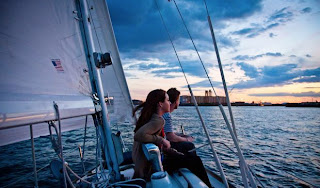 Source: Unknown A young woman and man sitting on the edge of a sailboat enjoying the sunset