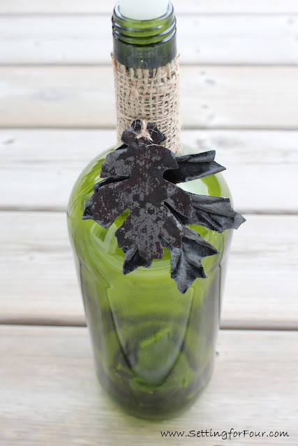 Easy DIY Home Decor Idea: DIY Wine Bottle Candle Holder with burlap and painted leaves.