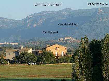La masia de Can Pasqual amb els Cingles de Capolat al seu darrere, des dels camps de La Cabana La masia de Can Pasqual amb els Cingles de Capolat al seu darrere, des dels camps de La Cabana