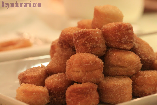 A pile of cronut holes or crobits sprinkled with sugar.