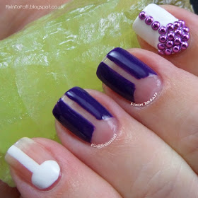 Nail art based on a 1960s mod theme, featuring negative space patterns and purple studs.