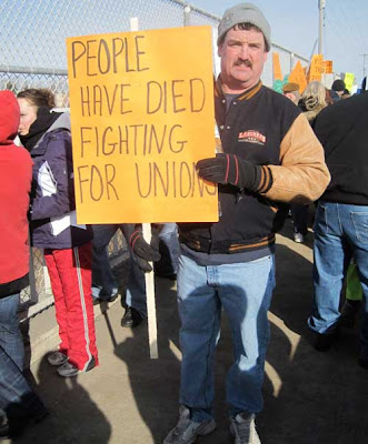 Man with sign reading People have died fighting for unions