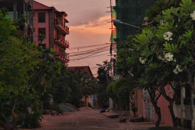 Phnom Penh 5h du matin Courte série de clichés prise lors d'un départ de la ville qui s'éveille vers la campagne. Phnom Penh et ses alentours à cinq du matin c'est l'occasion d'admirer l'aube qui se fissure, les éclairages bleutés et orangés, une ville qui ne bourdonne pas encore, une quiétude encore unique.