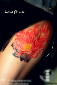 a vivid red lotus flower tattoo on the thigh