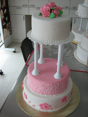 A very elongated 3 tier cake with pink white and soft green color 
