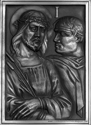 Bronze relief in black in white of Station one of the Stations of the cross.