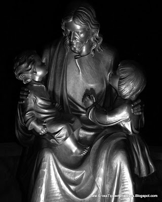 Night picture of large gray statue of Jesus holding children.