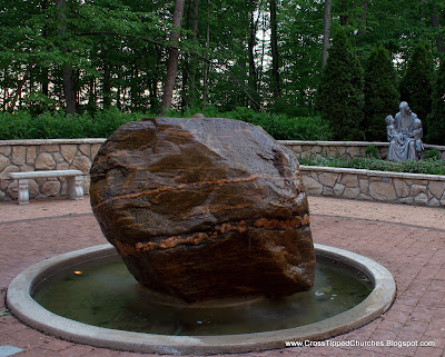 Large stone fountian with statue of Jesus holding children in the background.