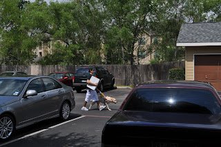 Darrell walking down the parking lot with a big white box in his hand and Egypt's harness in the other - dog included of course, this shot is from the patio of our apartment right as Darrell is walking between two cars