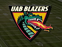 Yellow, red, black, and green triangular shaped UAB Blazers logo with fire breathing dragon is set against the backdrop of a green computerized football grid iron.