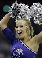 A blonde University of Memphis cheerleader wearing a blue top and holding silver pom poms over her head.