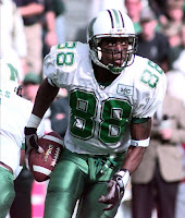 Wide receiver Randy Moss carrying a football in a green and white Marshall University uniform.