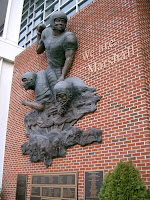 We are Marshall red brick wall memorial of three bronzed football players.