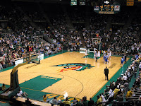 Fans fill a basketball arena with a green dragon breathing fire design drawn on the center of the court.
