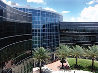Blue mirrored exterior of a ten story academic building with palm trees set in the front landscape of a UCF building.