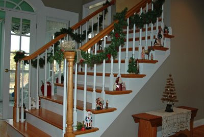 small Santas line the main stairway underneath pine rope garland, while a brown silk thread tree rests on the hallway bench