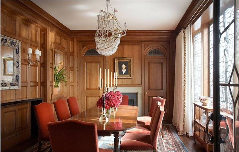 Traditional dining room by Katie Leede with wood paneling, a crystal ship chandelier over an oval table and rust colored velvet chairs