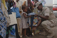 Navy Senior Chief Legalman Alicia Barnes hands a book bag containing school supplies, flip flops, soap, shampoo and treats to a young girl at The Center for the Protection of Women and Children, the largest orphanage in Djibouti. (U.S. Navy photo)