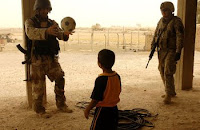 A Iraqi soldier and an American Soldier play with a child as his family speaks with the Iraqi Army and Coalition troops about activity in their area July 29 in the al Jazeera desert near Balad, Iraq. (Army photo by Staff Sgt. Micky Bazaldua)