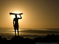 Surfista observa as ondas ao por do sol.
