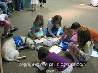Rocky in a down stay surrounded by kids coloring at church.